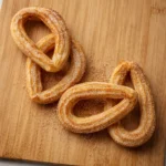 Churros caseros en air fryer dorados y crujientes con azúcar sobre tabla de madera, textura real y acabado premium