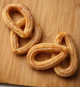 Churros caseros en air fryer dorados y crujientes con azúcar sobre tabla de madera, textura real y acabado premium